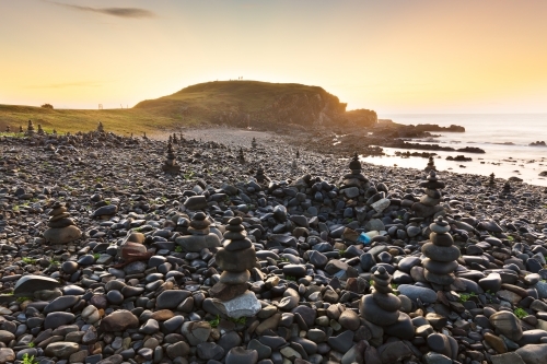 A series of rock piles on a rocky beach at sunrise - Australian Stock Image