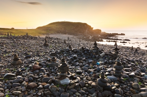 A series of rock piles on a rocky beach at sunrise