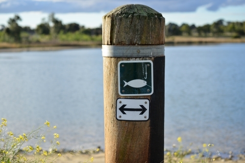 A sign post advising people that fishing is allowed on this side of the lake