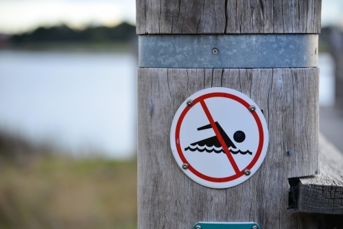 A sign post advising the public not to swim in this lake