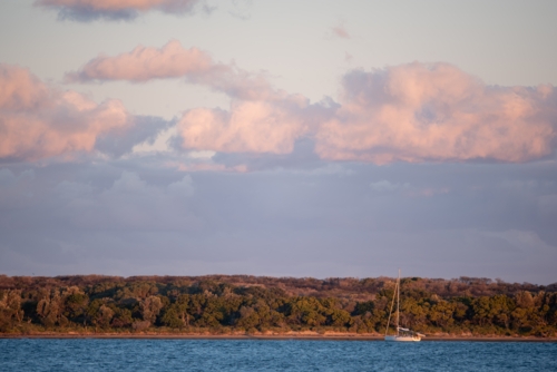 A single yacht moored off Jibbon point at sunset - Australian Stock Image