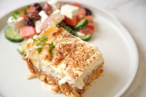 a slice of baked dish with fresh vegetable salad on the side - Australian Stock Image