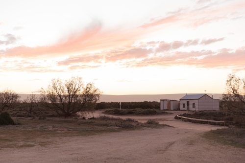 A small house under a cloudy sky with soft hues of pink and orange - Australian Stock Image