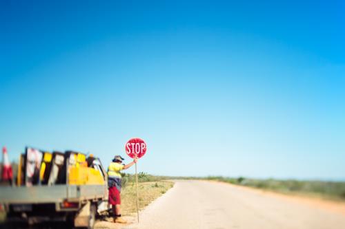 A solitary road worker holds a stop sign on a deserted road in the middle of nowhere