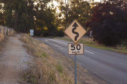 A speed and windy road sign in a country setting - Australian Stock Image