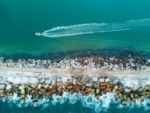 A speed boat travelling along a break wall - Australian Stock Image