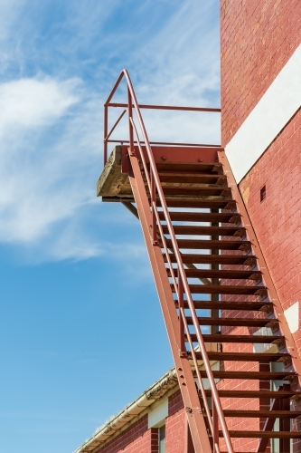 A steel staircase leading up the outside of a brick wall - Australian Stock Image