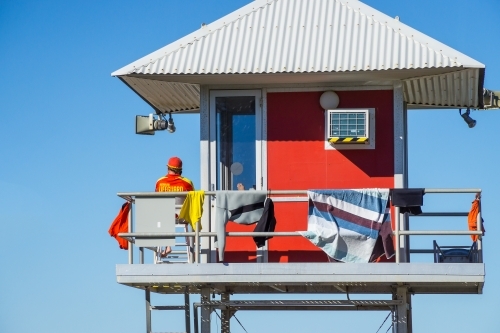 A surf lifeguard sitting in a watch tower with a corrugated tin roof. - Australian Stock Image