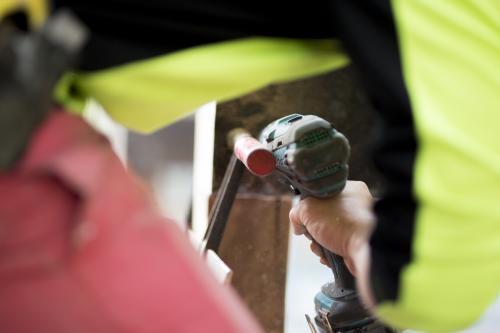 A tradesman drills into a wooden beam. - Australian Stock Image