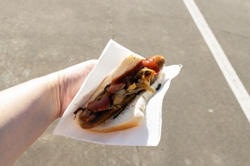 A traditional Australian barbequed sausage in bread with onions and tomato sauce - Australian Stock Image