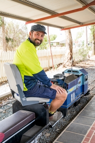 A train driver sitting aboard the controls of a miniature train - Australian Stock Image