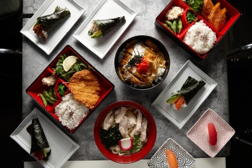 A variety of Japanese dishes in a square and rectangular plates arranged in a marble surface - Australian Stock Image