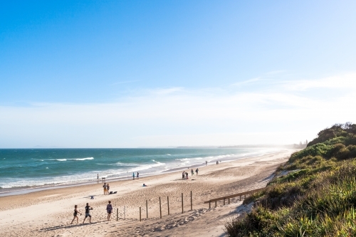 A variety of people and families enjoy a summers day holiday at long beach - Australian Stock Image