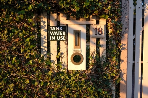 A vertical letterbox built into a fence bathed in sunlight - Australian Stock Image
