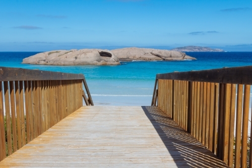 A view of a walkway leading to the blue waters of a beach