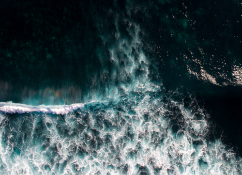 A wave breaks over a dark ocean - Australian Stock Image