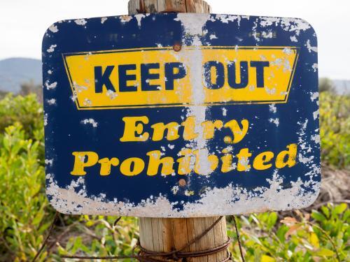 A well worn "KEEP OUT Entry Prohibited" blue and yellow sign