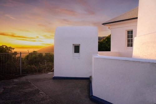 A white building with metal railings with sun setting in the background - Australian Stock Image