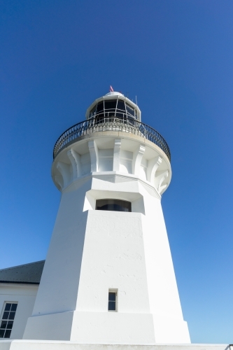 a white lighthouse with small windows under a clear blue sky - Australian Stock Image