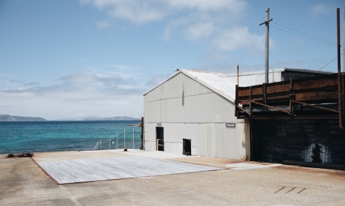 A white warehouse beside the shore at the Old Whaling Station - Australian Stock Image