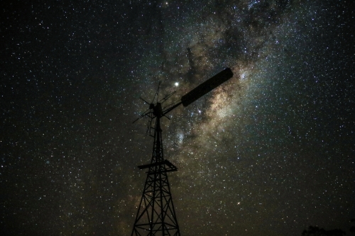 A windmill under a sky filled with stars showcasing a prominent Milky Way galaxy - Australian Stock Image