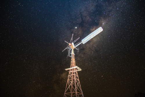 A windmill under a sky filled with stars showcasing a prominent Milky Way galaxy - Australian Stock Image