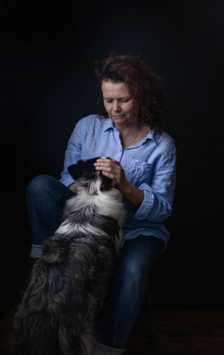 A woman in a blue shirt with her black and white dog - Australian Stock Image