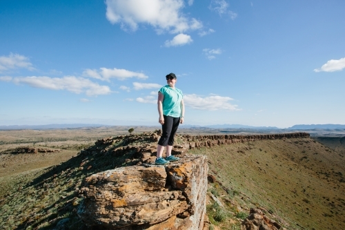 A woman in hiking gear overlooking the rugged landscape of the Flinders Ranges - Australian Stock Image