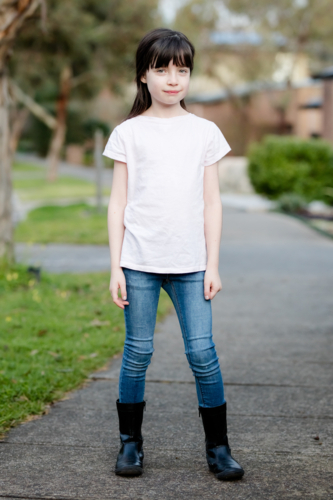 A young caucasian girl poses in the street with plain clothing on a sunny evening in Australia - Australian Stock Image