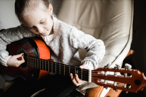 A young caucasion girl practicing playing her guitar - Australian Stock Image