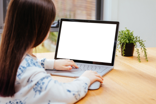 A young female child uses a computer in remote learning for her school work - Australian Stock Image
