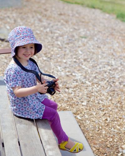A young girl / child sitting on a chair, smiling and taking photos - Australian Stock Image