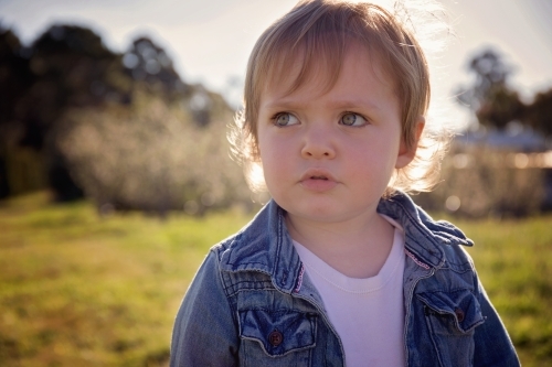 A Young Girl Looking Away From the Camera With Her Hair Backlit - Australian Stock Image