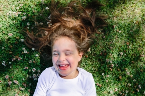 A young girl lying in a field laughing