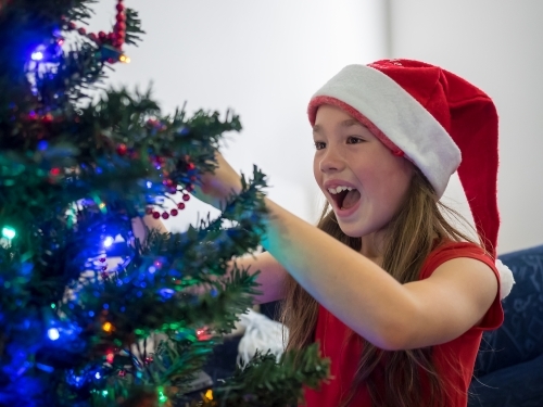 A young girl of mixed race decorating a Christmas tree