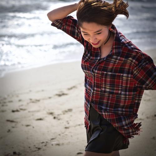 A young woman enjoying the sun on the beach by the water - Australian Stock Image