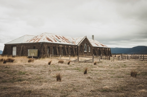 abandoned bluestone shearing shed in the dry grassy landscape