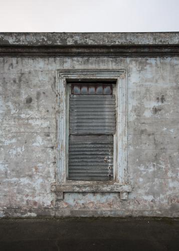 Abandoned grey building and shuttered window