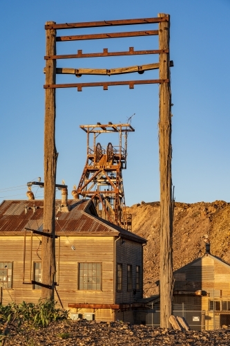 Abandoned mining structures and poppet head tower with late afternoon lighting