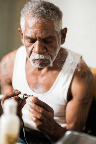 Aboriginal Artist at Work with a Wood Burner - Australian Stock Image