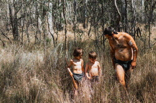 Aboriginal Australian father teaching children on country - Australian Stock Image
