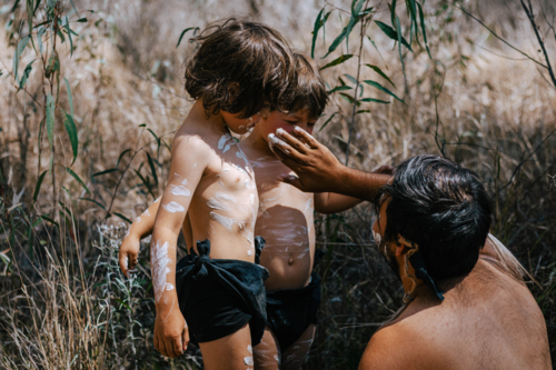 Aboriginal Australian painting the faces of his children - Australian Stock Image