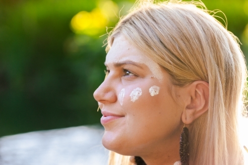 Aboriginal Australian woman on country in traditional dreamtime ochre body paint looking away - Australian Stock Image