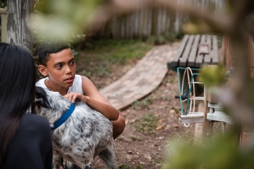 Aboriginal boy and girl with dog in backyard - Australian Stock Image
