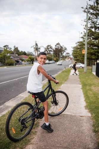 Aboriginal boy riding bike on footpath - Australian Stock Image