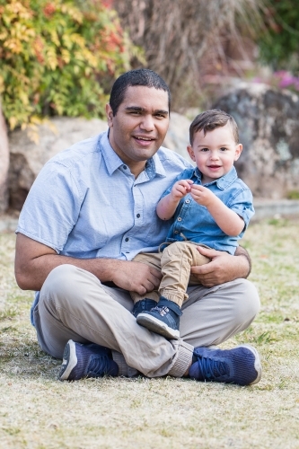 Aboriginal caucasian mixed race son sitting with father smiling