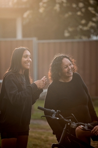 Aboriginal family in backyard daughter laughing with mother - Australian Stock Image