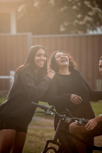 Aboriginal family in backyard mother and daughter laughing - Australian Stock Image