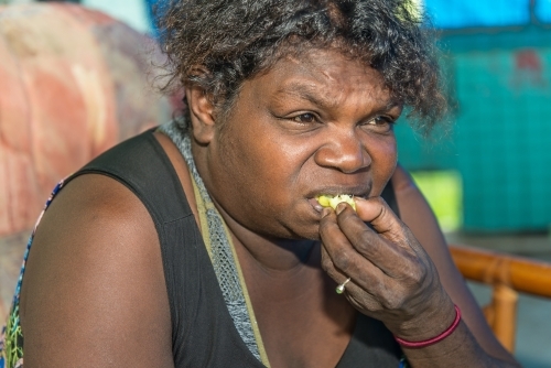 Aboriginal female eating Kakadu Plum - Australian Stock Image