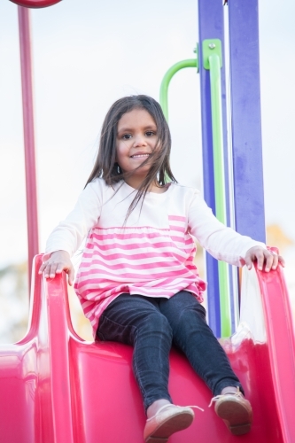 Aboriginal girl on slide at park - Australian Stock Image